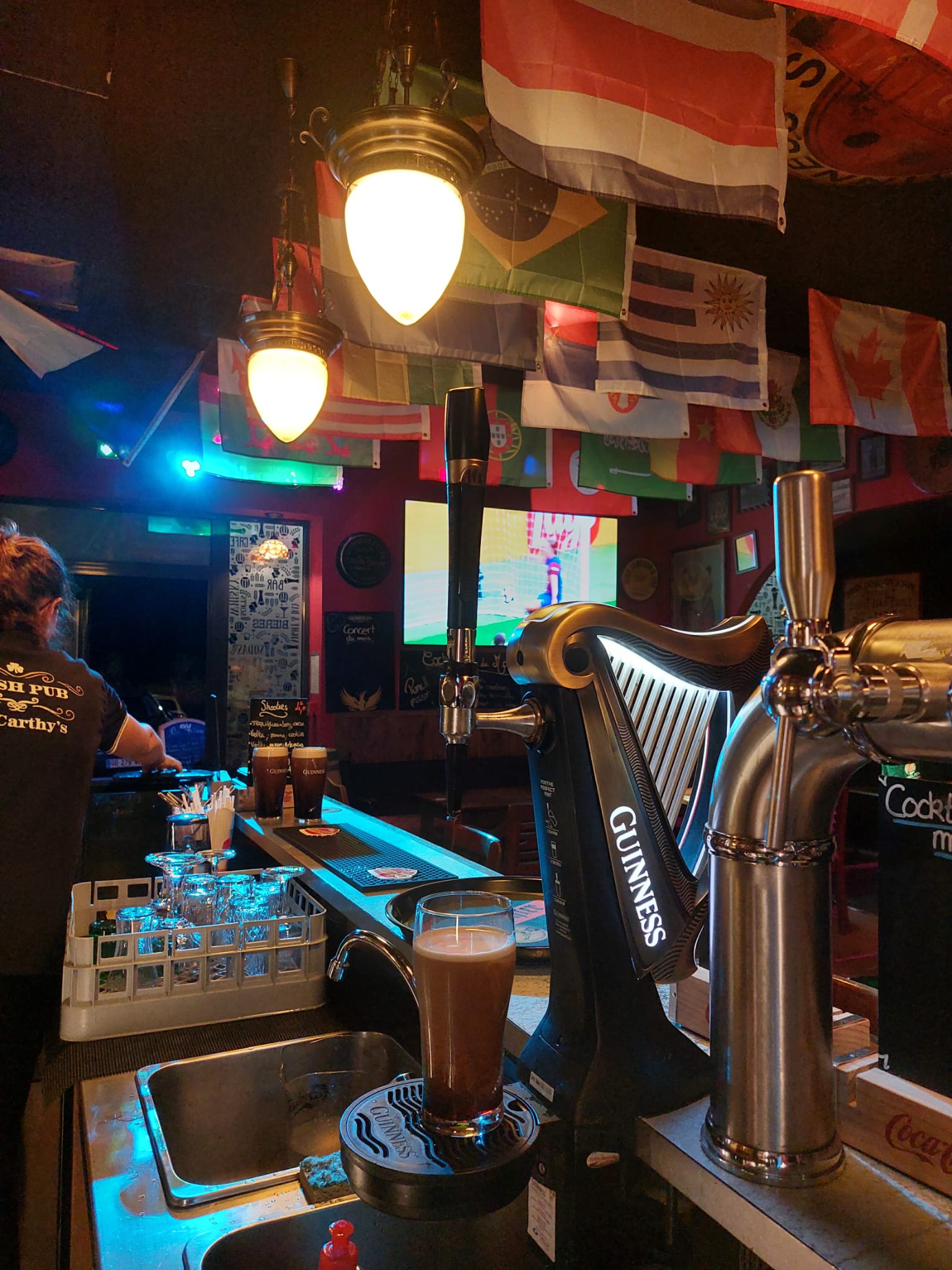 Pub avec drapeaux et verre de bière sur comptoir.