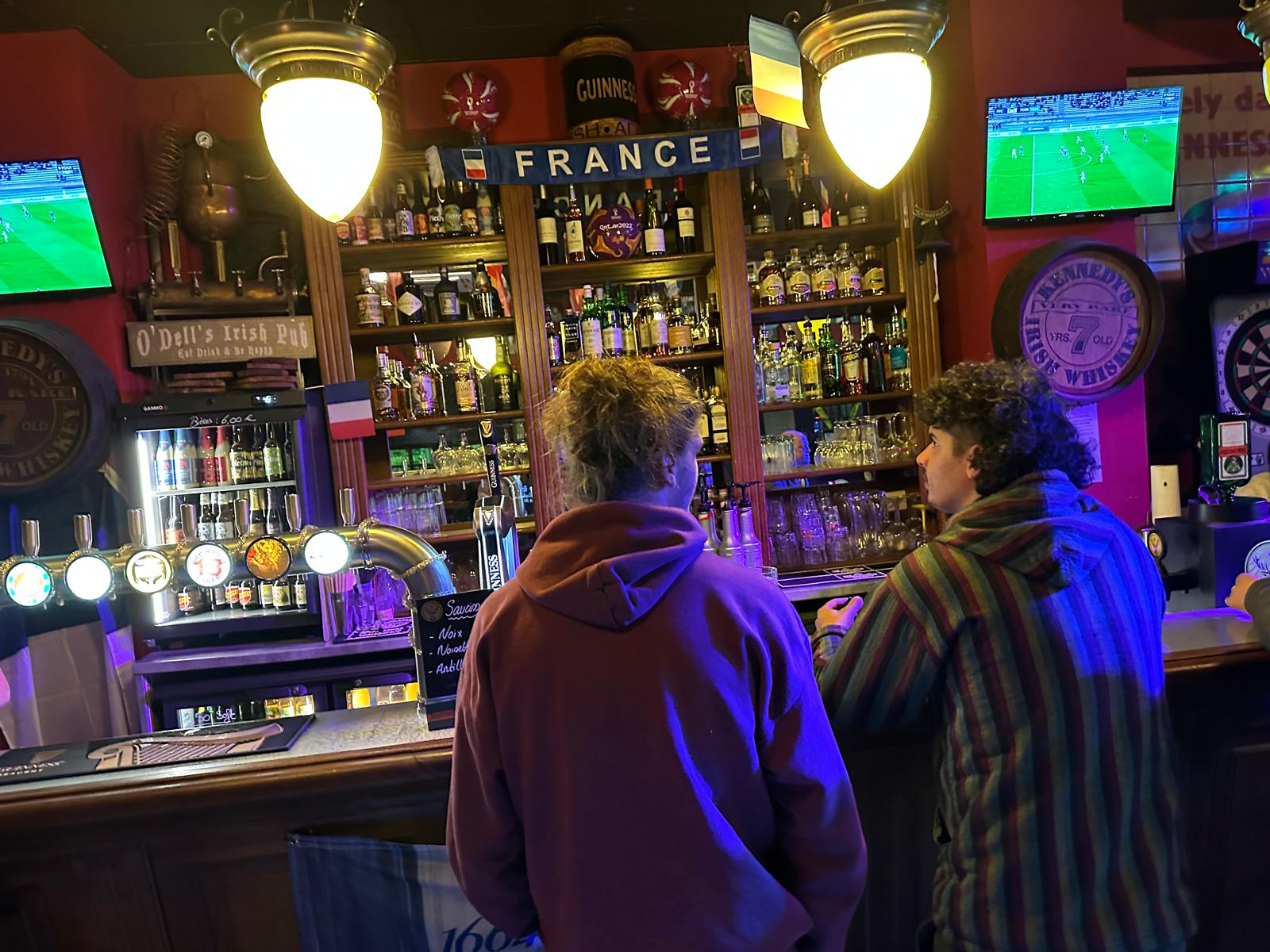 Deux personnes au bar regardant des écrans.